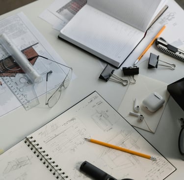 Carnet de croquis avec dessin de façade, plans d'architecte et lunettes sur un bureau en bois