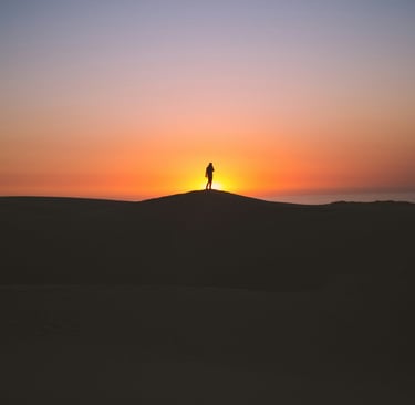 Lone hiker silhouetted at sunrise on desert hill, symbolizing solitude, strength, and new beginnings