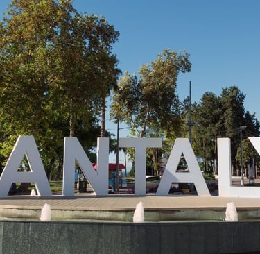 Praça em Antália com o letreiro da cidade ao fundo.