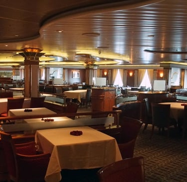 Restaurante elegante a bordo de navio de cruzeiro, com mesas arrumadas, iluminação suave.