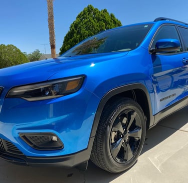 a newly detailed blue jeep parked in front of a palm tree