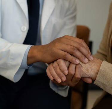 Neurology provider offering supportive care, holding a patient’s hand during consultation.
