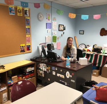 a teacher sitting at a desk in a classroom