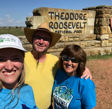a man and two women standing in front of a sign that says theodore roosevelt national park