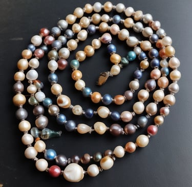 A close-up view of an intricately designed piece of jewelry featuring a large, raw green gemstone. The gemstone is encased in a silver-colored metal setting with swirling patterns and small decorative silver balls.