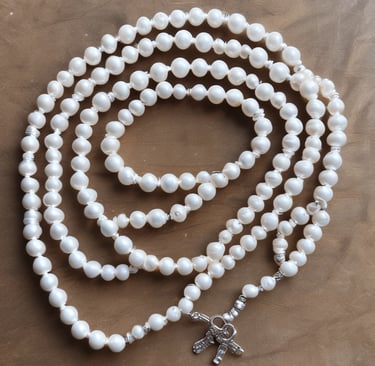 A gold pendant with matching earrings, intricately designed with teardrop shapes adorned with small, sparkling stones. The jewelry set rests against a wooden background, with delicate chains and clasps visible. The shine and elegance of the pieces suggest they are crafted for special occasions.