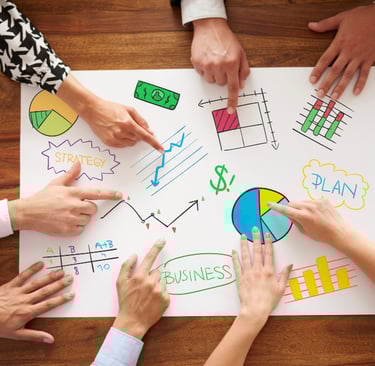 a group of people sitting around a table with a paper board with a diagram of