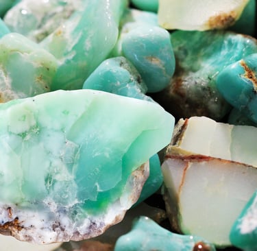 Collection of raw, polished green chrysoprase and teal turquoise gemstones in a close-up pile.