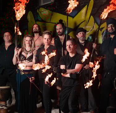 Flame Syndicate fire and music team pose in front of a wall full of graffiti art
