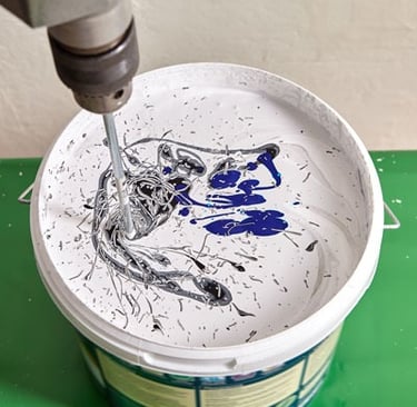 a person using a drillet to paint a bucket