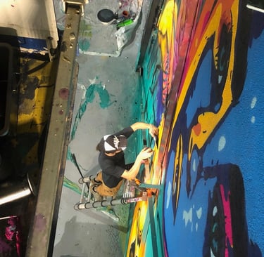 un homme vu de haut entrain de peindre une fresque sur une échelle 