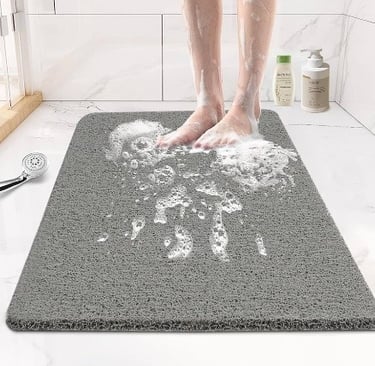 a person standing on a non-slip bathroom rug with a shower head and soap on the mat