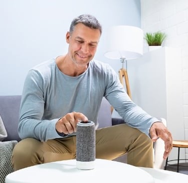a man sitting on a couch touching his Allexa home monitor