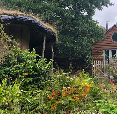 beautiful wild garden with a cob round-house and a wooden built house