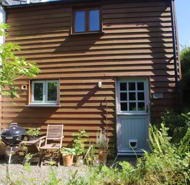 Holiday rental exterior front courtyard with chair and BBQ