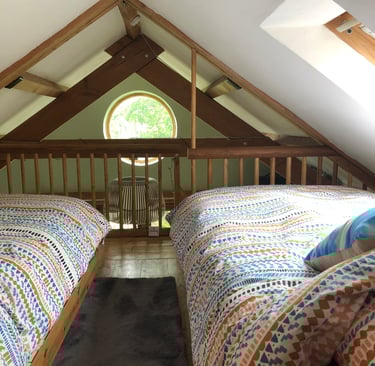 Holiday rental interior showing mezzanine twin beds overlooking circular window