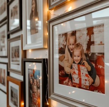 a wall of framed photographs of family photos and family photos
