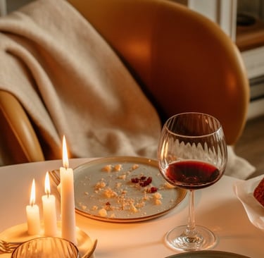 A candlelit winter dinner table after guests have left — glowing candles, half-filled glasses, and c