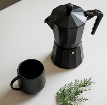 a coffee potted on a table with a cup of coffee and a plant