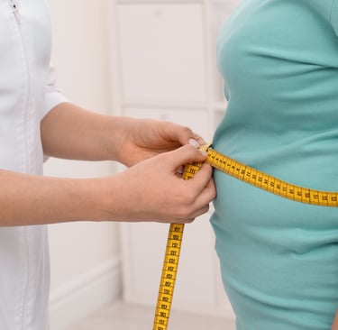 A doctor measuring a patient's waist with a yellow tape measure during a weight loss consultation.