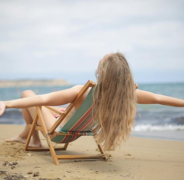 Woman in Blue and Brown Bikini Sitting on Brown Wooden Folding Chair on Beach