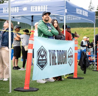 People standing by a sign that says "The Dock" drinking beer.