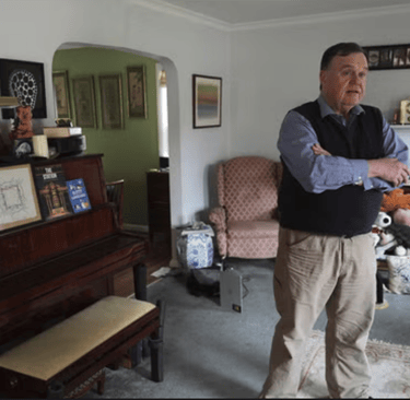 a man standing in a living room with a piano