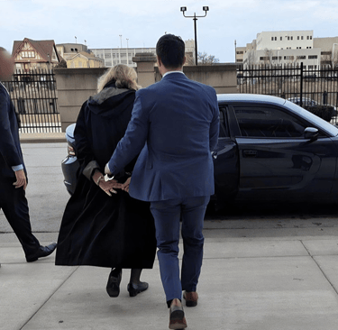 a man in a suit and tie walking away from a car