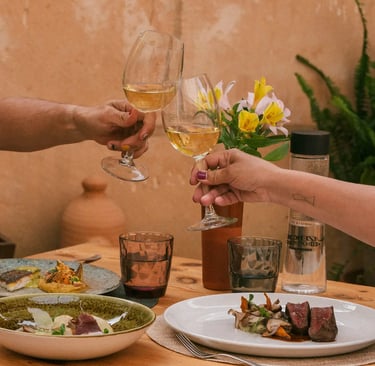 Copas de vino blanco, solomillo con guarnición, alcachofas con jamón y chips y pescado del día servido en Es Mestral.