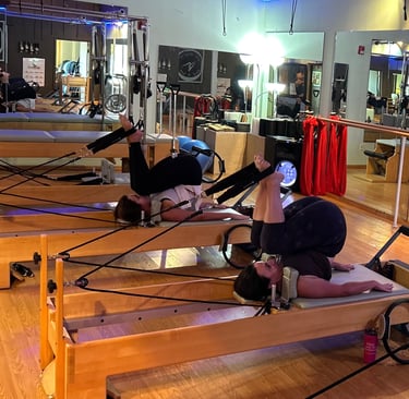 two women working out on pilates reformers