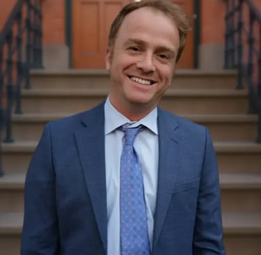Attorney Jay Browne smiling in front of a Brownstone 