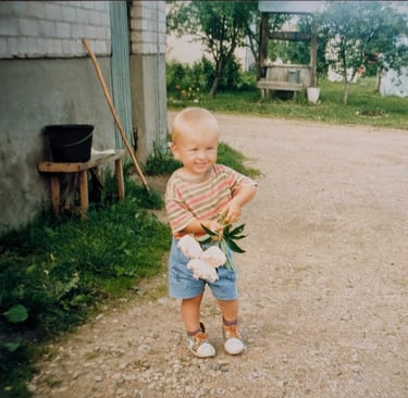 a young boy holding peony blossoms in a driveway