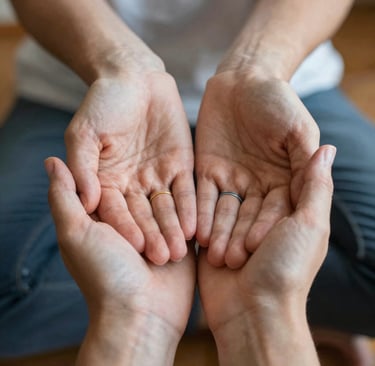 A couple wearing wedding bands holding hands together in a gesture of support and partnership.