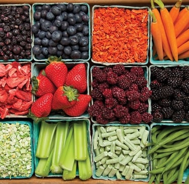 Variety of fresh and dried fruits and vegetables like berries, carrots, and beans in a wooden crate.
