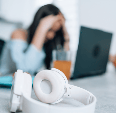 a woman sitting at a table with a laptop and headphones