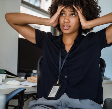 Une jeune femme noire aux cheveux crépus qui se tient la tête entre les mains