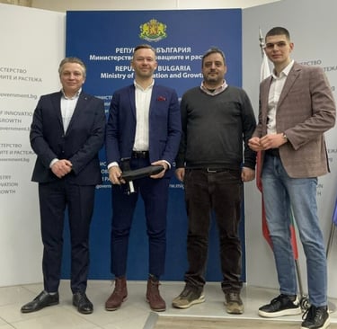 Four men standing in front of the Republic of Bulgaria Ministry of Innovation and Growth banner.