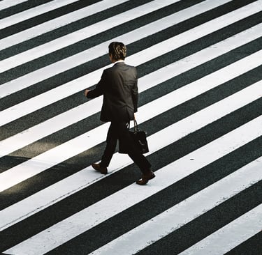 a man in a suit and tie walking across a crosswalk