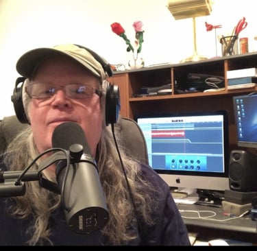 a man with long hair and glasses on a microphone