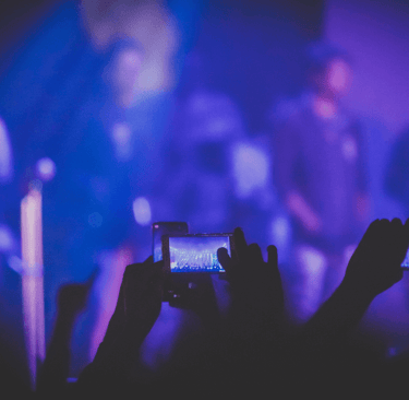 a person holding a cell phone in front of a stage