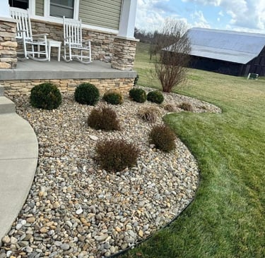 Decorative rock landscaping with shrubs and stonework around a residential home by Valor Home Professionals
