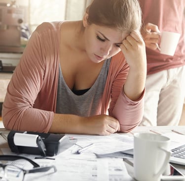 Young casual female having depressed look while managing family finances and doing paperwork