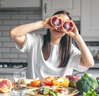 Happy young woman with orange halves in the kitchen