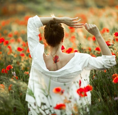 a woman in a white dress standing in a field of flowers