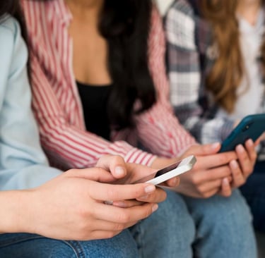 a group of people sitting on a bench with cell phones