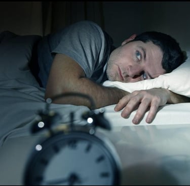 a man lying in bed with a clock on the side