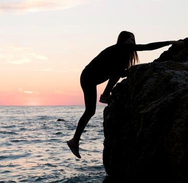 a woman standing on a rock in the ocean