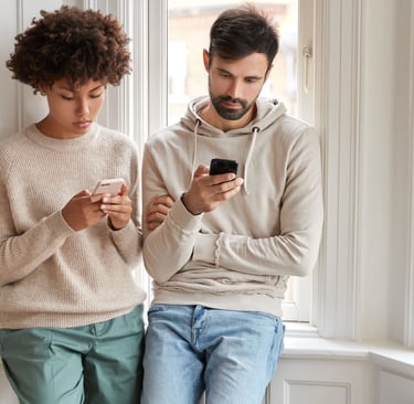 a man and woman standing next to each other and texting