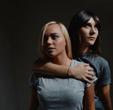 two women standing next to each other in a dark room