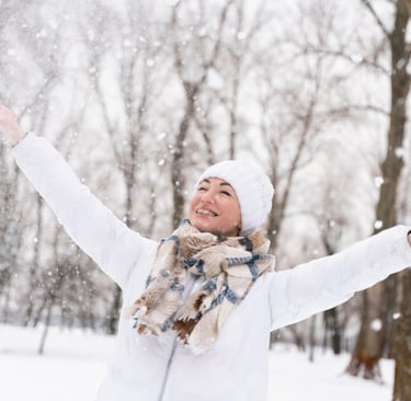 femme avec bonnet et echarpe dans la neige qui sourit